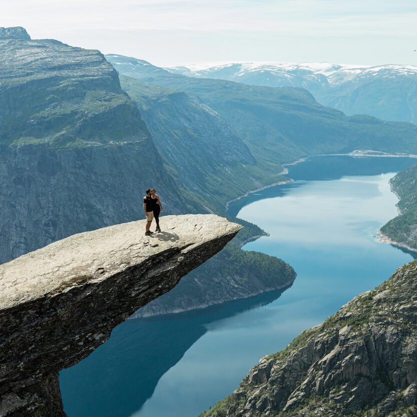 A happy couple standing on the Trolltunga cliff, Vestland county, Norway